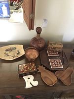 Vintage cheese cutting board with wooden nut bowls, leather wrapped bottle, wooden decorative boxes, and candy basket on display