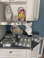 Group photo of 8 aluminum cake pans with cartoon character shapes including bear, turtle, and a duck wearing a top hat.