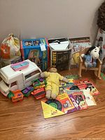 Wide view of lot showing boxed Lite-Brite and Fisher Price Movie Viewer, Barbie Camper, Cabbage Patch doll, records, books, and toys.