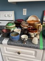 Overview of dishware and pottery collection on countertop, including plates, bowls, vases, and accessories