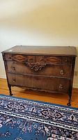 Front view of mid-size wood dresser showing four drawers with carved details and metal ring pull handles.