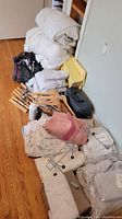 Photo showing folded comforters, stacks of sheets, bundled mattress cover, multiple wooden and plastic hangers, a suitcase, and hair curlers.