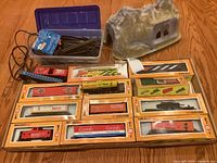 Overall lot image showing multiple Cox HO scale model trains in original yellow and orange boxes, a plastic box with HO scale track pieces and transformer, and one resin tunnel.