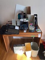 Photo of all office supplies arranged on a wooden desk including digital photo frame box, bins, binders, calculator, computer speakers, photo paper, CDs, hanging files, and folders