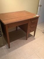 Full view of solid oak desk showing four drawers on the right side and tapered legs.