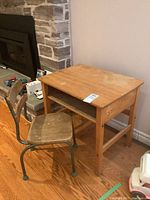 Image showing vintage child's school desk with light wood top and open shelf beneath, paired with a metal and wood chair.