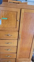Photo showing upper left cabinet door with a small knob handle and four drawers beneath with metal handles, displaying wood grain and some wear.