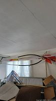Windsurf board and attached sail rigging hanging from ceiling in a room with furniture around