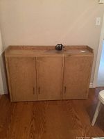 Front view of plywood wooden cupboard with three doors and pencil sharpener on top