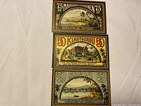 Photo of three antique German Notgeld banknotes from 1922, showing detailed front designs and colors of each note.