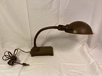 Full view of vintage gooseneck electric lamp showing dome-shaped shade, gooseneck arm, rectangular base and attached cord.