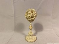 Front view of the vintage Canton puzzle ball on its stand against a neutral fabric backdrop.