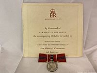 Full view of the medal in front of the official certificate showing the crown emblem and text