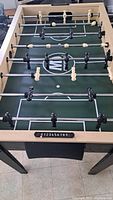 Foosball table playing field and rods from above showing player figures and scoring system.