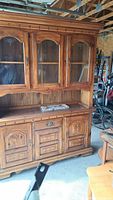 Front view of wooden hutch showing three glass panel doors with sandblasted designs and lower drawers/cabinets.