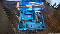Photo of Makita jigsaw in blue case with Ryobi detail sander still boxed, and Sears Craftsman circular saw on the side.