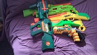 Six various Air Blast Sidewinder air blasters in multiple colors including green, yellow, orange, and teal, laid out on a purple surface.