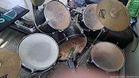 Black acoustic drum kit featuring bass drum, snare, toms, hi-hat, cymbals