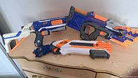 Five Nerf blasters positioned on a dresser showing their side profiles.