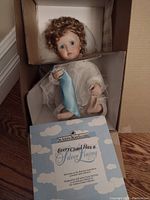 Doll displayed in original box with certificate showing title and designer information.