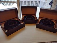 Three Kodak Ektagraphic Model 2 universal slide trays in brown boxes, arranged on a table with windows in the background.