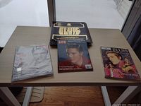 Wide image showing entire Elvis Presley memorabilia collection on table including four main book and record items.