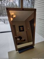 Rectangular mirror with grey metal frame, displaying reflections of a room and window outside with snow, showing condition and style details.