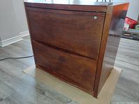 Photo of a two-drawer wood finish file cabinet with lock on upper drawer, showing overall condition and wood texture.