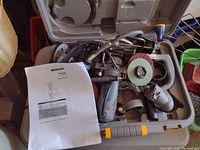 Motocraft Spin Saw with multiple attachments and instruction manual inside a gray carrying case