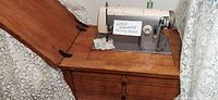 Vintage Kenmore sewing machine set in a wooden cabinet with foot pedal.
