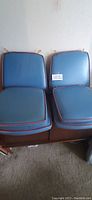 Six blue vinyl chair cushions arranged on a sofa, showing front side with red piping and string ties for attachment.