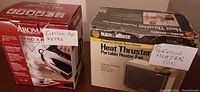 Photo of boxed Black & Decker Heat Thruster portable heater fan and boxed Aroma Hot H2O X-Presso electric kettle with handwritten labels.
