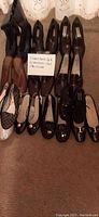 7 pairs of ladies dress shoes in sizes 9 and 4, and 1 pair of kid shoes arranged on carpet with a note listing quantities and sizes.