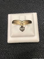 Yellow gold triple band ring with a small heart-shaped diamond pendant shown from front.