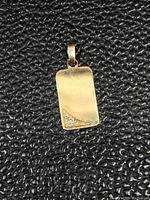 Front view of a rectangular 10Kt gold pendant with a small cluster of three diamonds in the bottom corner.