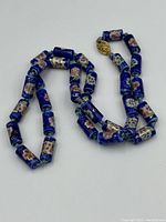 Photo of the Chinese export porcelain necklace showing cylindrical, floral-patterned blue beads and gold-toned clasp.
