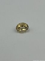 Pale yellow oval faceted citrine gemstone displayed on a white background.