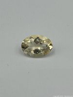 Top-down clear view of a faceted oval citrine gemstone showing light yellow color and transparency on a white background.