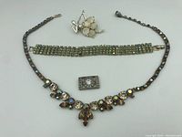 Necklace, bracelet, and brooch laid out flat on white background showing overall condition and design.