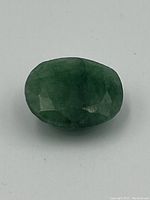 Top view of faceted green emerald gemstone showing oval shape and natural inclusions.