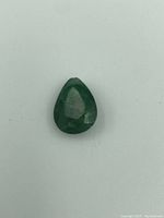 Front view of the pear-shaped emerald gemstone on a white background.