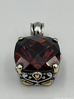Front view showing faceted garnet and silver prongs with gold-tone accents