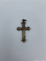 Front view of a small gold fill Victorian cross pendant against a white background highlighting the engraved decorative details.