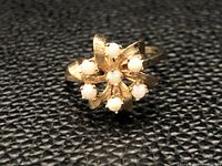 Front view showing the gold ring with eight small round opals arranged in a cluster on textured petal-like gold setting.