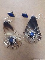 Pair of large tribal dangling sterling silver earrings with teardrop shape, filigree style cutouts, and central oval lapis lazuli stone in each