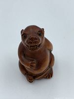 Front view of a small hand-carved boxwood animal netsuke with detailed face and limbs.