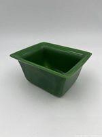 Front angle view of the square jade green dish showing the flared rim and smooth surface.
