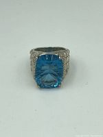 Front view of sterling silver ring with large cushion-cut blue gem showing detailed facets and prong setting