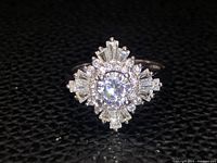 Close-up view of the sterling silver ring showing the central round clear gemstone with surrounding baguette and round clear stones.