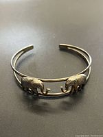 Front view of vintage sterling silver open cuff bracelet with two detailed elephant figures facing each other.